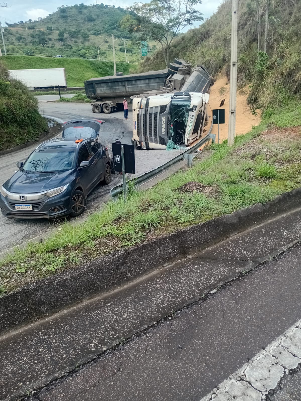 A cabine da carreta, com o para-brisa quebrado, e a caçamba virada na curva de acesso à BR-381. Foto: Redação Rádio Cultura