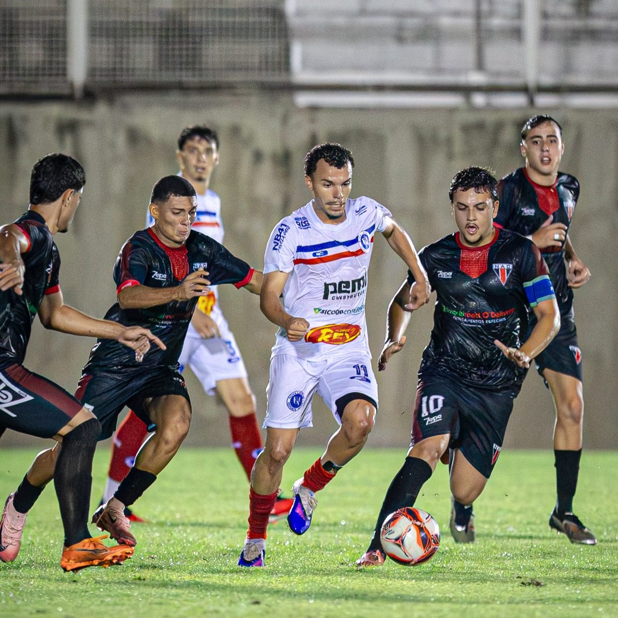 Nova Lavras, de branco, em lance contra o Nacional em Muriaé